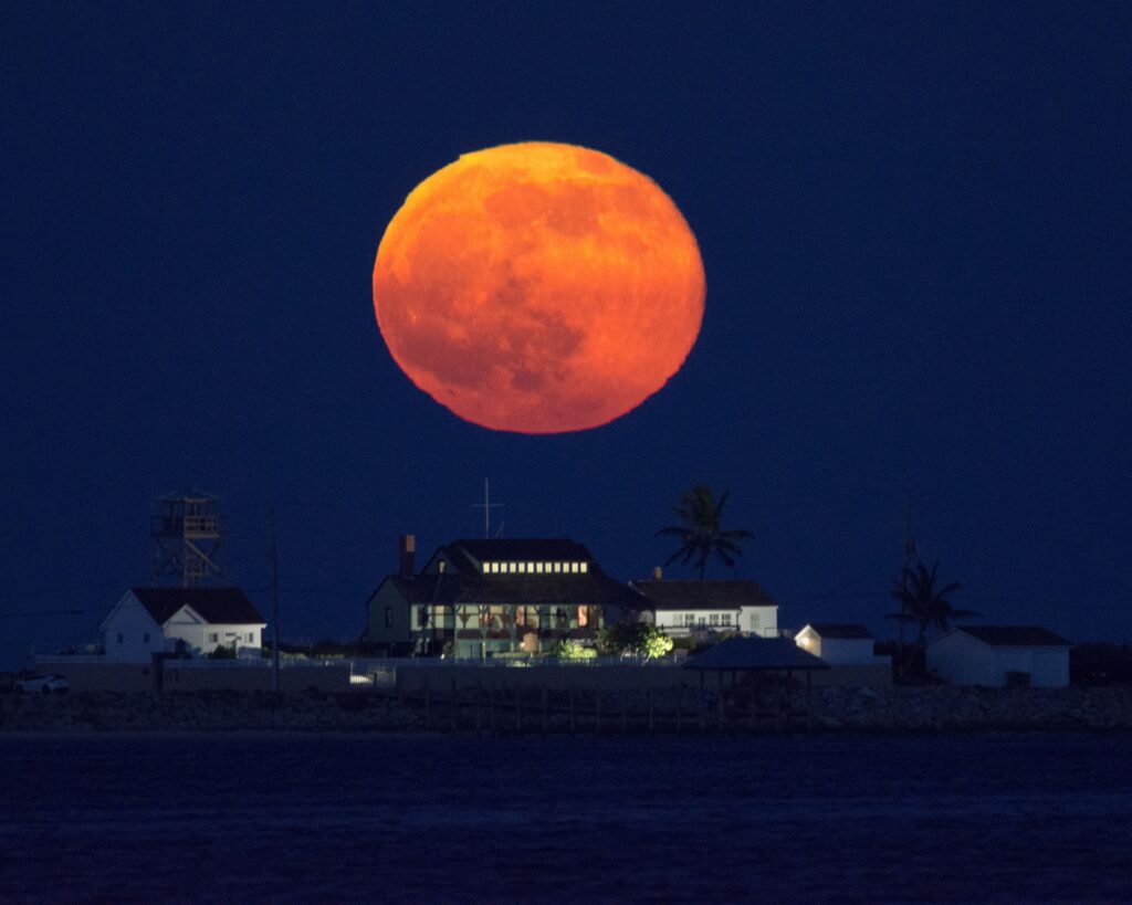 large orange moon over a store